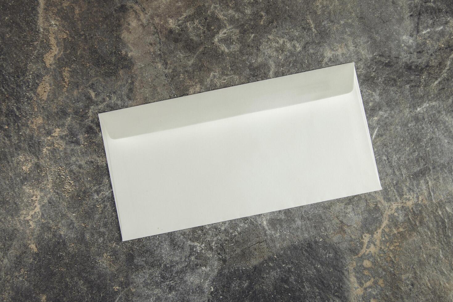 An empty white envelope on a stone surface photo