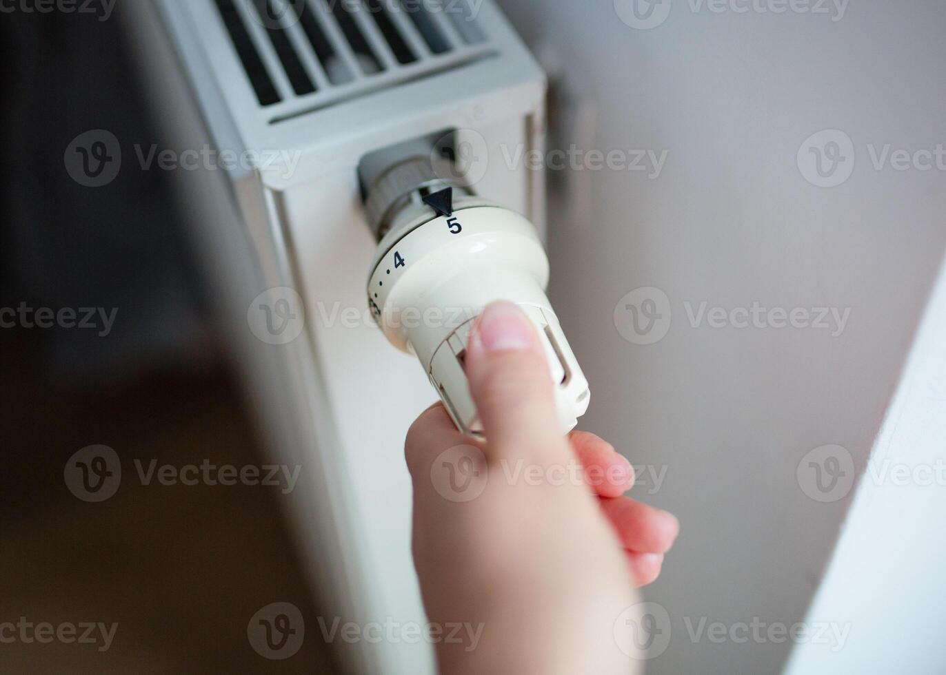 Person adjusting a thermostatic valve on a home radiator. Concept of energy efficiency, home heating, and temperature control. photo