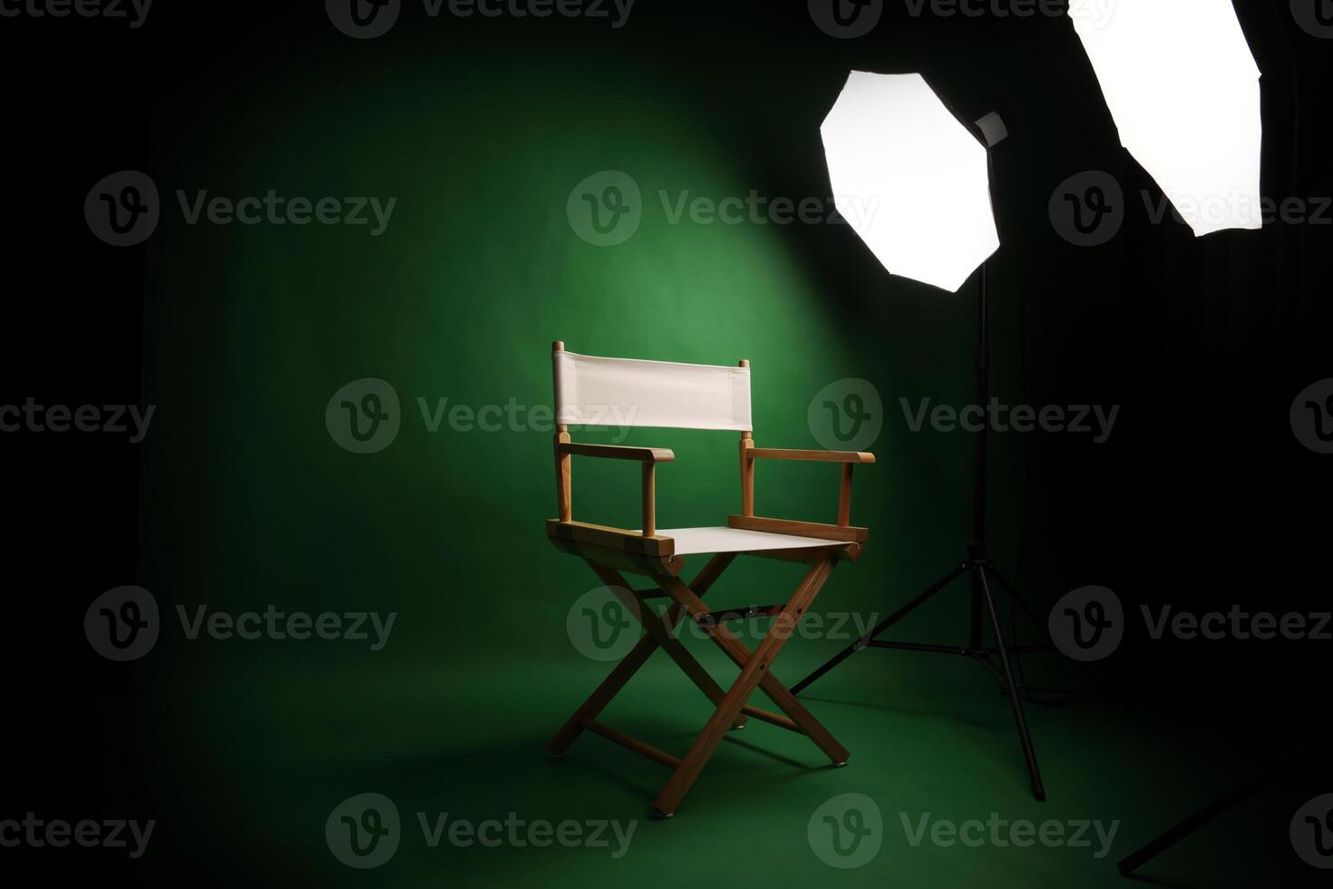 Photo studio with green screen background and wooden stool against professional lighting equipment. Interior of photo studio with professional lighting equipment and director chair with green backdrop