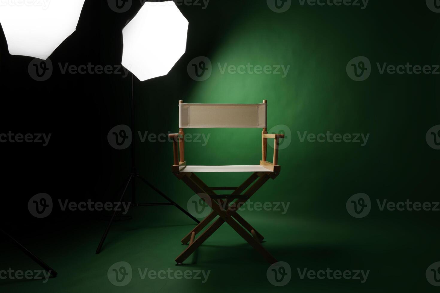 Photo studio with green screen background and stool against lighting equipment.