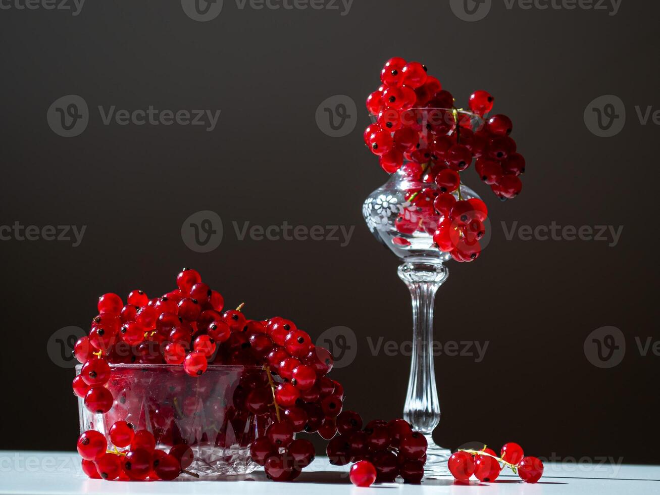 bunches of red currants in a glass goblet on a black background photo