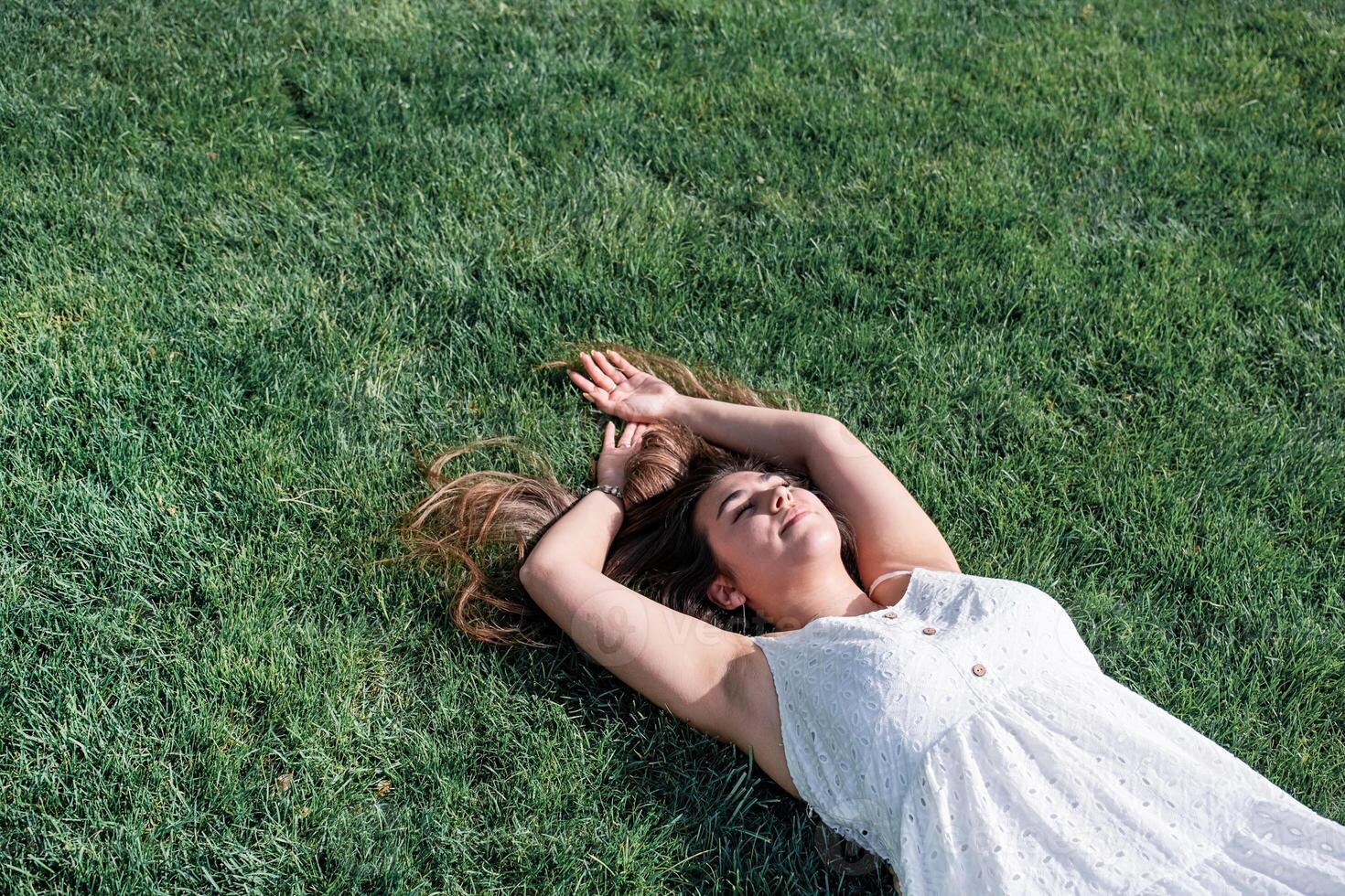 pretty young woman lying on green grass, copy space photo