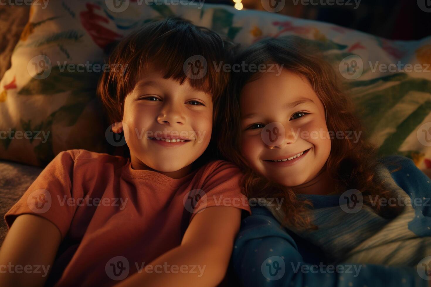 Two smiling children lying in bed together at night photo