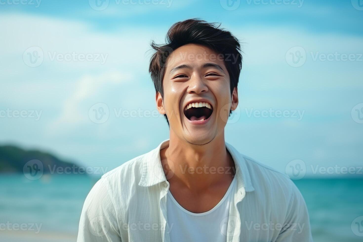 Happy asian man laughing out loud on tropical beach photo