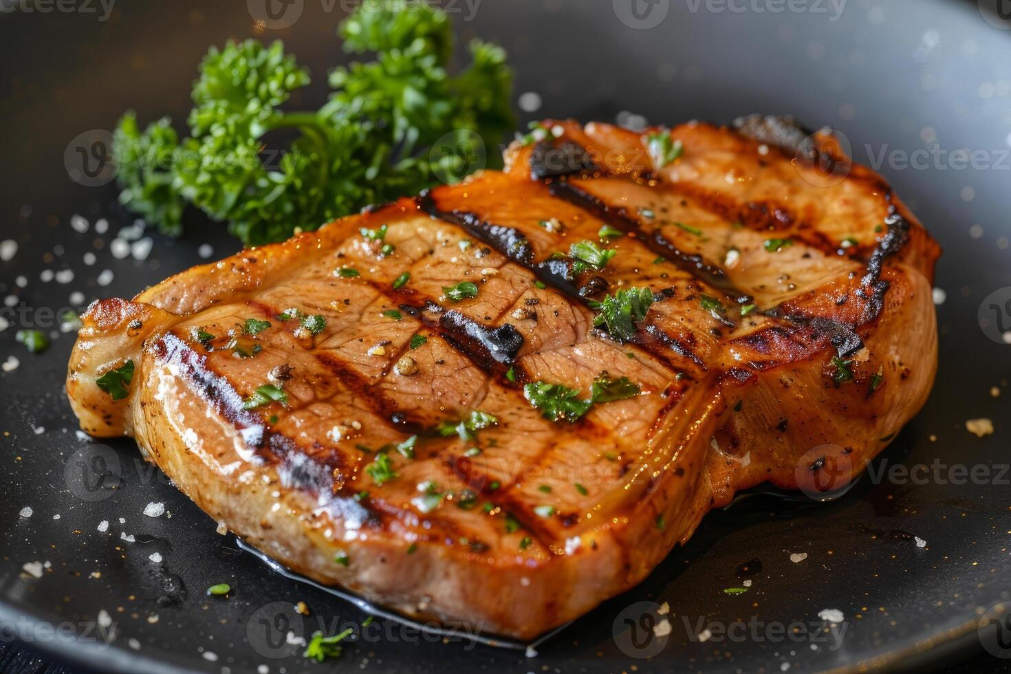 Grilled pork chop with parsley and salt on black plate photo