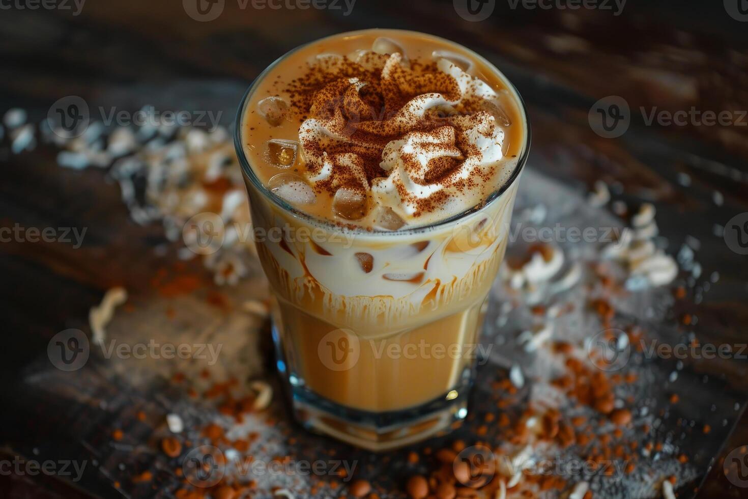 Iced coffee with whipped cream and cinnamon in a glass on rustic wooden table photo