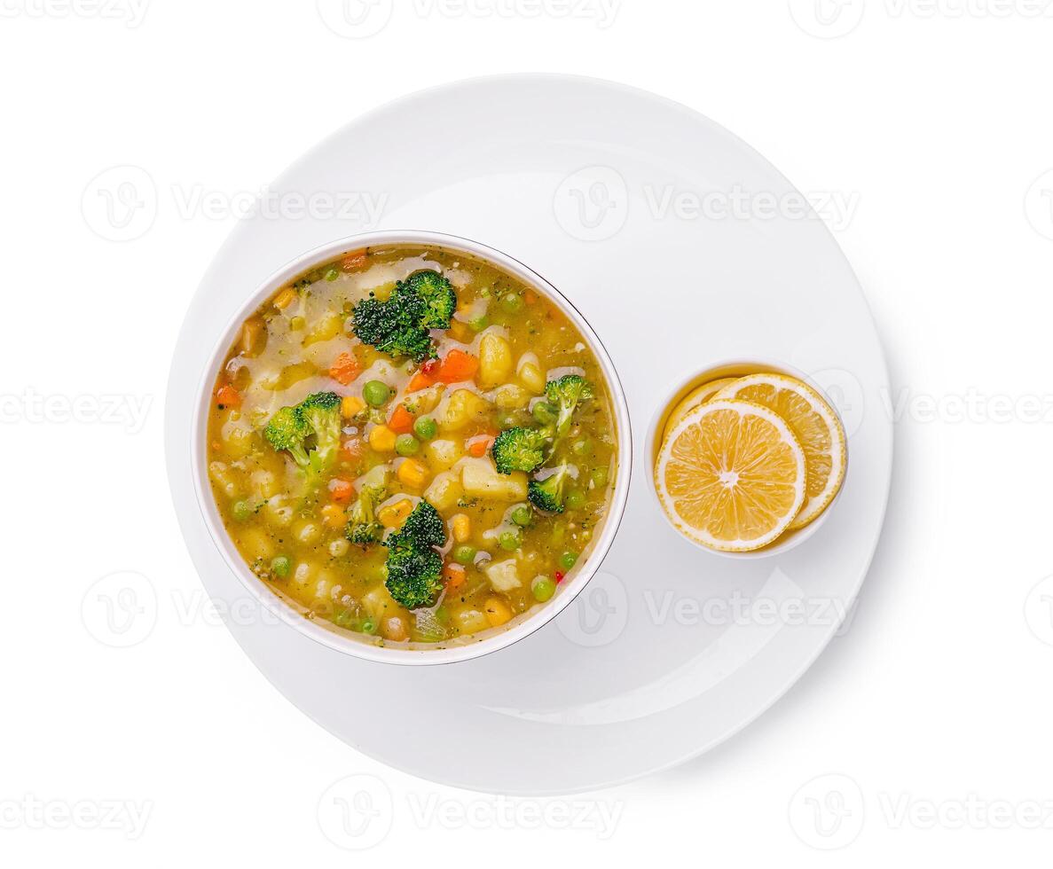 Delicious vegetable soup served in a bowl with lemon slices on the side photo