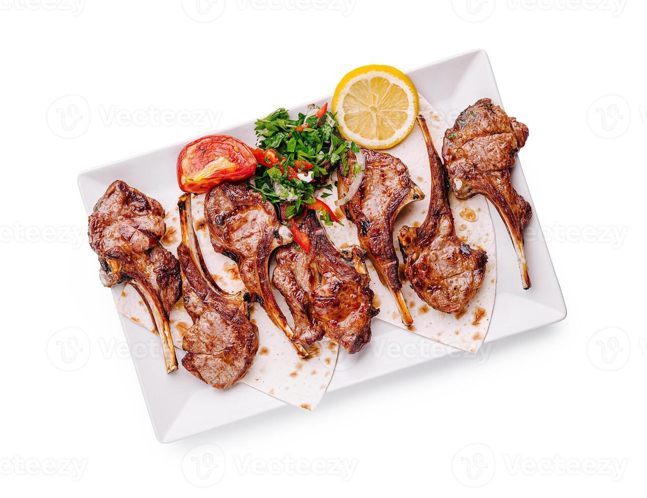 Grilled lamb chops served with fresh herbs and lemon on a clean white plate photo