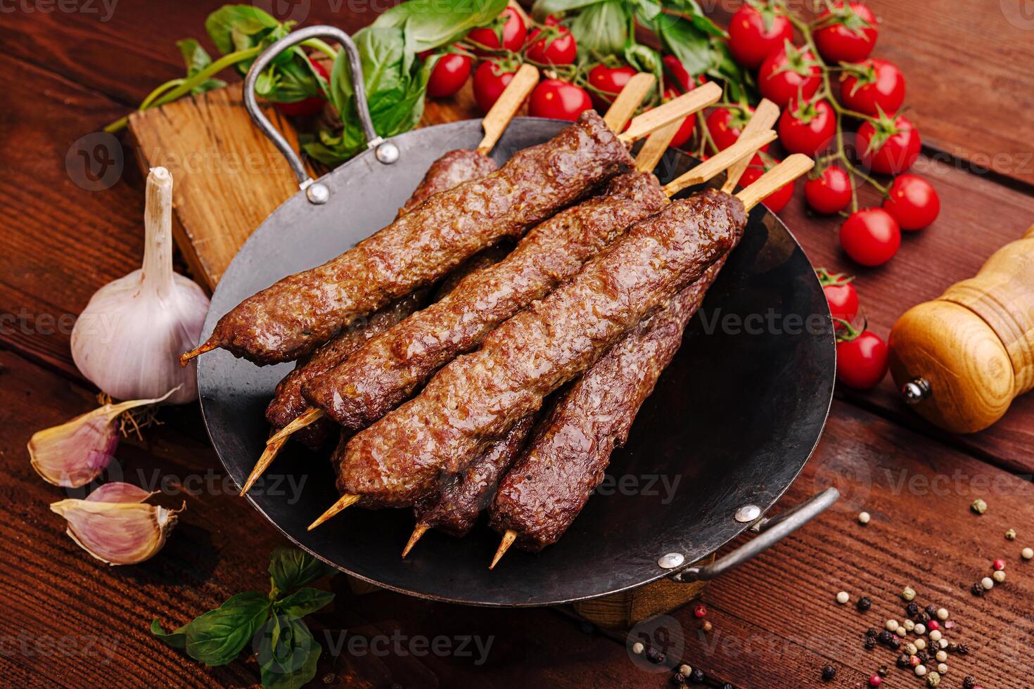 Grilled skewers of marinated meat served with fresh vegetables and spices on a rustic wooden table photo