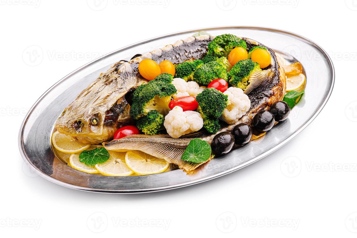Deliciously prepared whole fish garnished with fresh vegetables on a silver platter photo