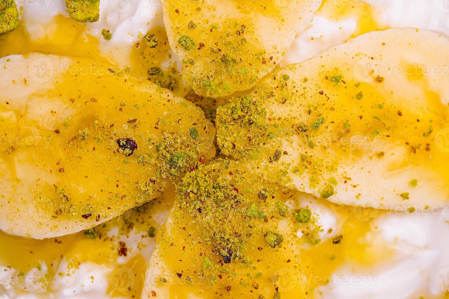 Delicious dessert featuring banana slices topped with honey and pistachios served in a bowl photo