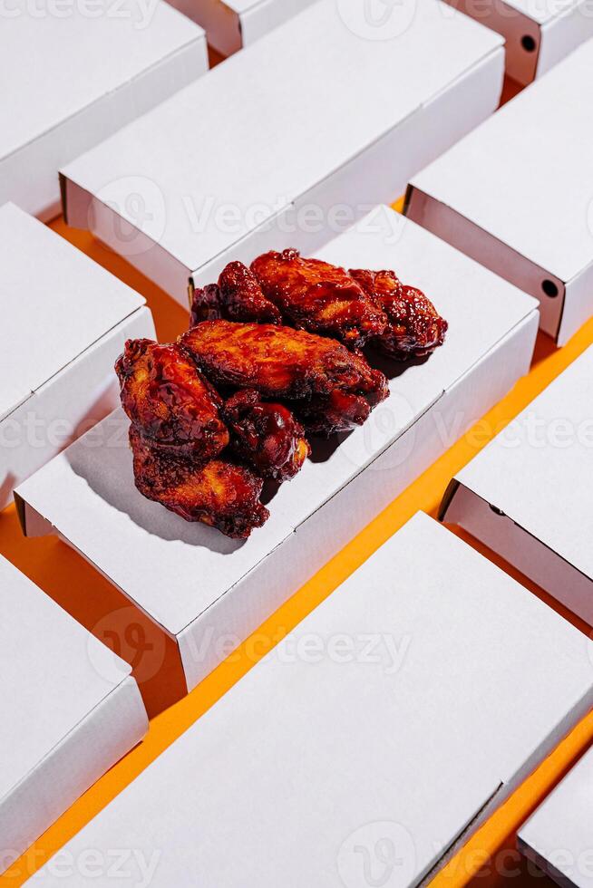 Delicious chicken wings served on orange background with multiple empty boxes surrounding them photo