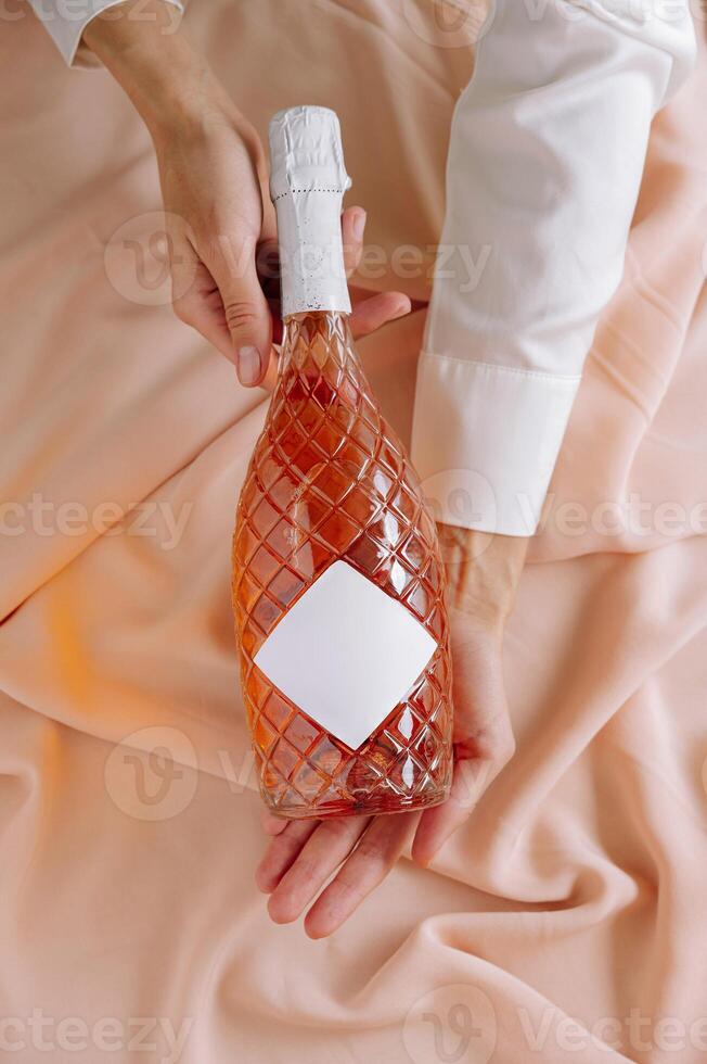 Elegant rose wine bottle held against soft pastel fabric, capturing a moment of celebration and indulgence photo