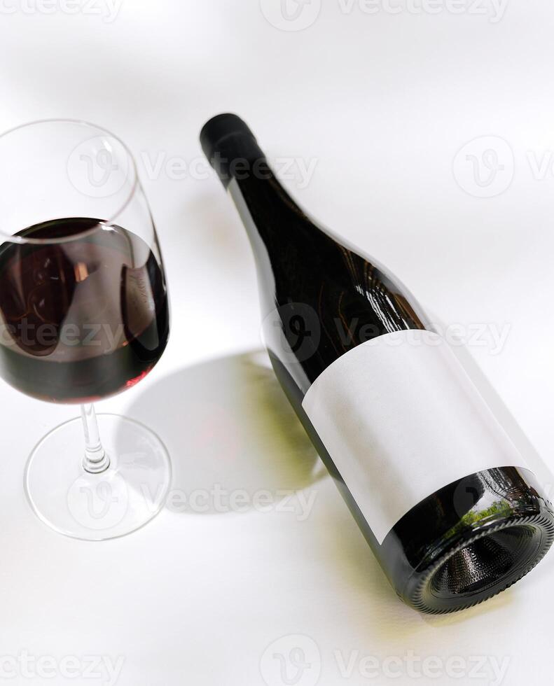 Dark red wine in glass next to an elegantly presented bottle on a neutral background photo