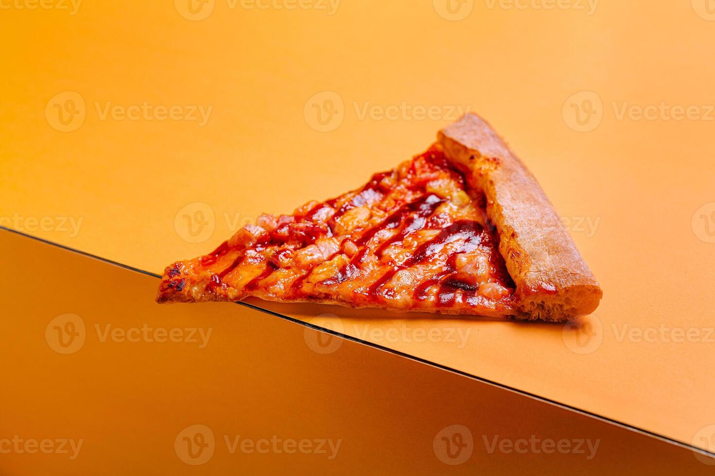 Slice of pizza resting on a vibrant orange surface showcasing melted cheese and toppings during a casual meal time photo
