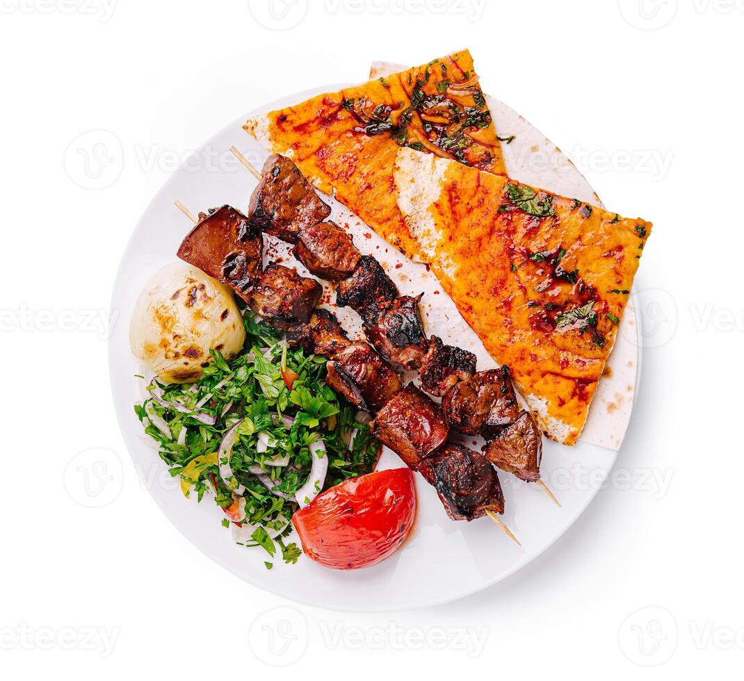 Delicious grilled skewers served with flatbread and fresh vegetables in a vibrant setting photo
