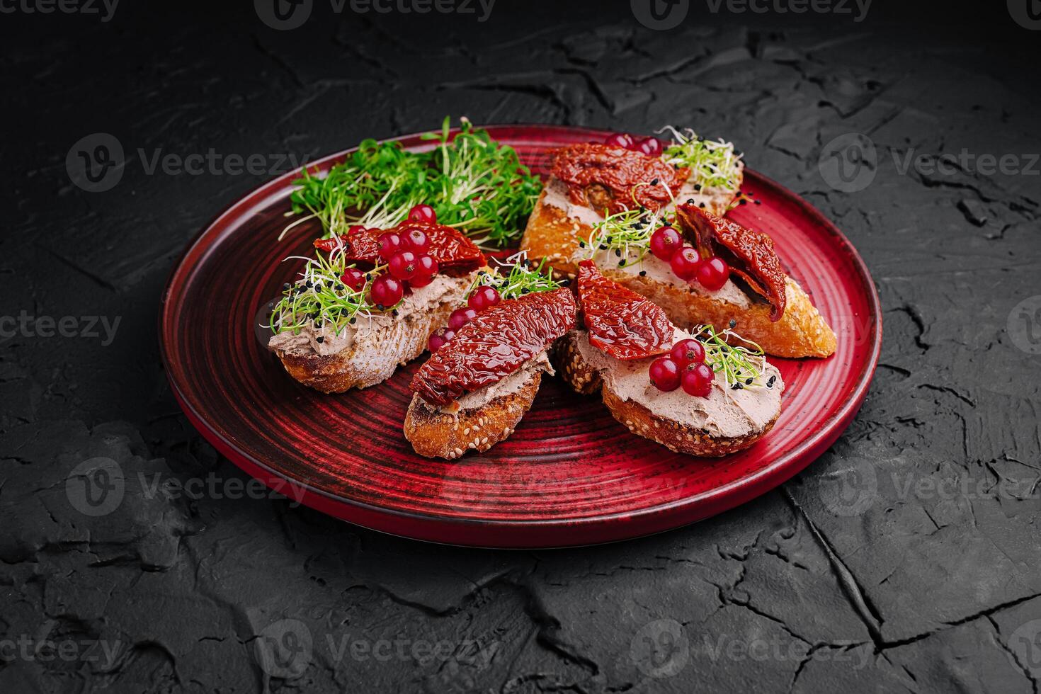 Savory bread slices topped with sun-dried tomatoes, sprouts, and red currants served on a vibrant plate photo