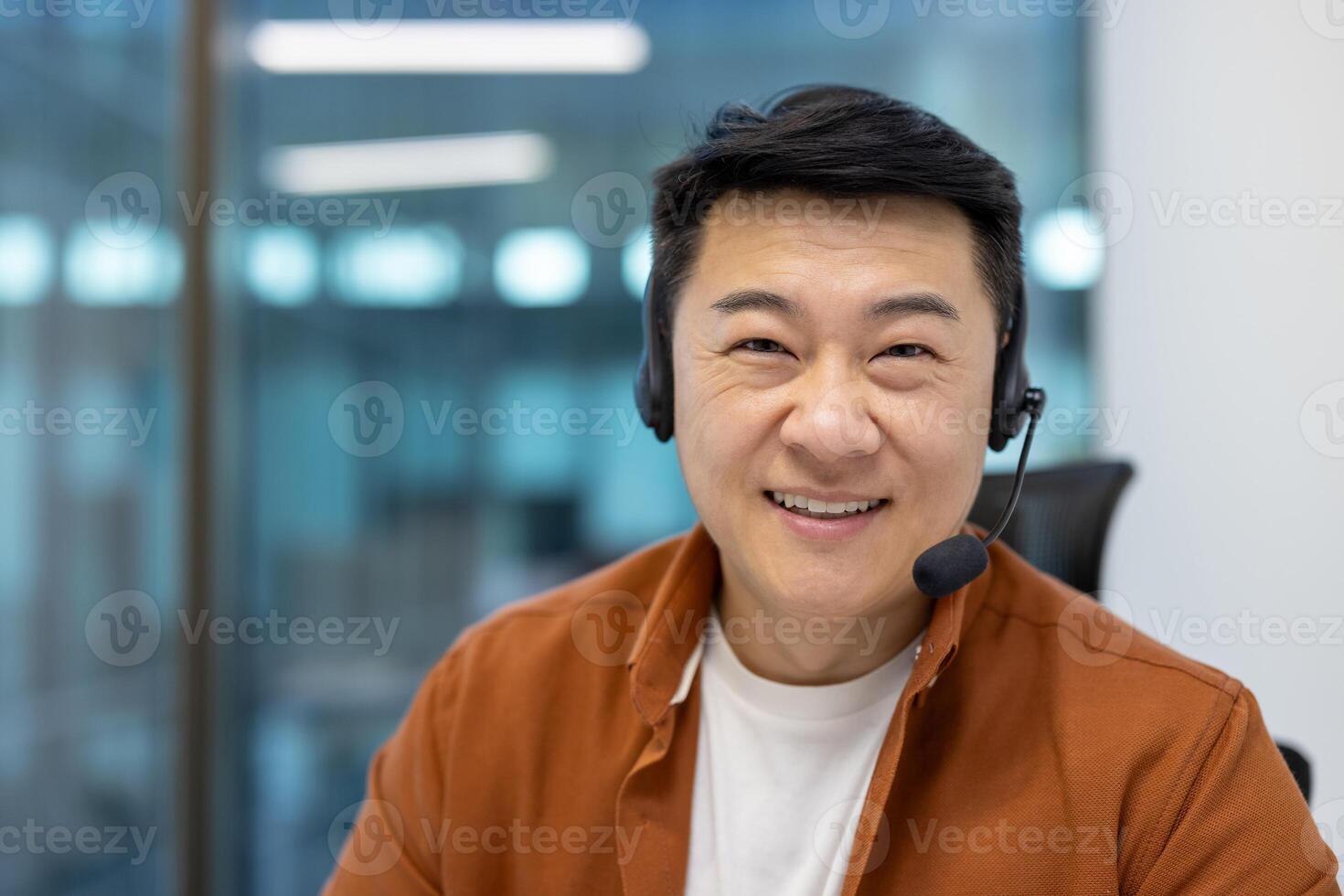 Asian man businessman with headset smiling in office. Engaging in online meeting or customer service, showcasing communication, professionalism, positive attitude, technology. photo