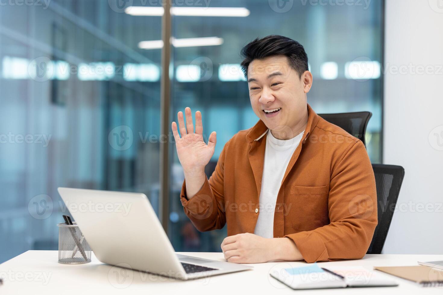 Asian man in a professional setting, engaging in an online call at work. photo