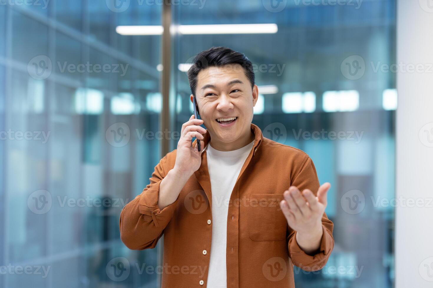 Asian man mature businessman engaging on a smartphone call, appearing cheerful and animated while interacting, symbolizing communication and professional engagement in a modern work environment. photo