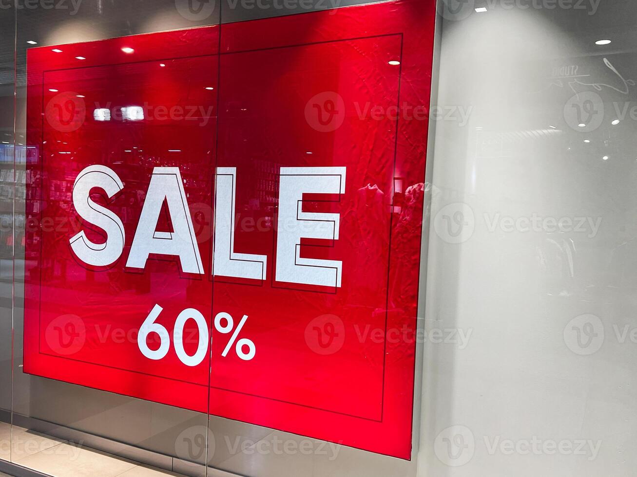 Red sale sign offering sixty percent discount inside a shopping store photo