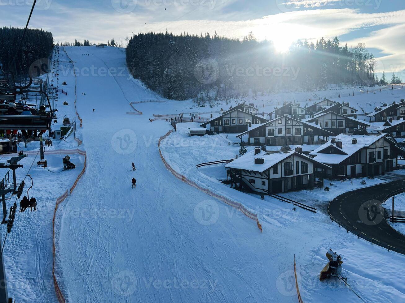 Winter ski resort with slopes, cabins, and scenic forest under bright sunlight photo