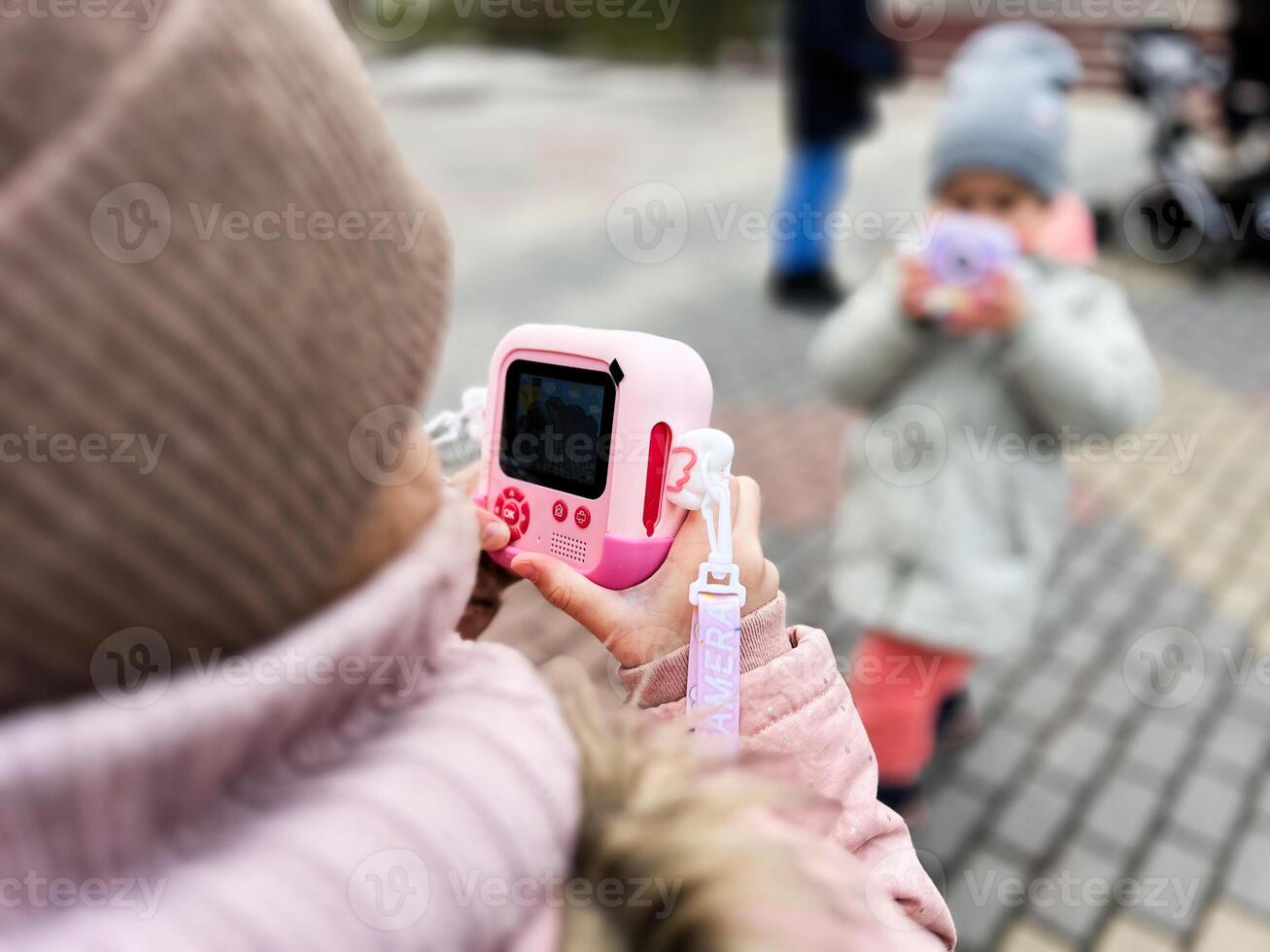 Children taking photos outdoors using toy cameras during cold weather