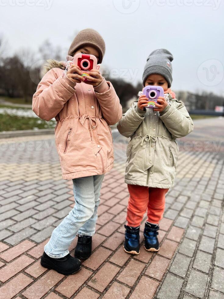 Children playing outdoors with colorful toy cameras during a winter day photo