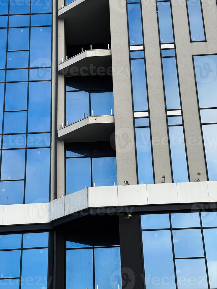 Modern glass facade of a commercial building with reflections and balconies photo
