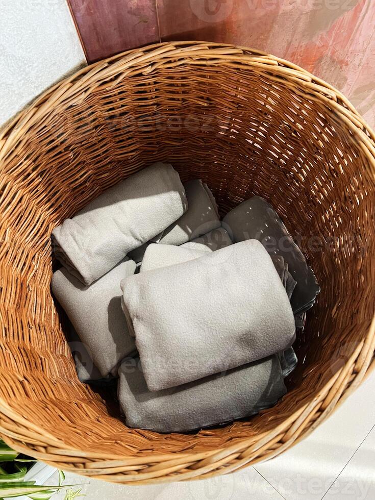 Wicker basket containing neatly folded gray towels in a well-lit setting photo