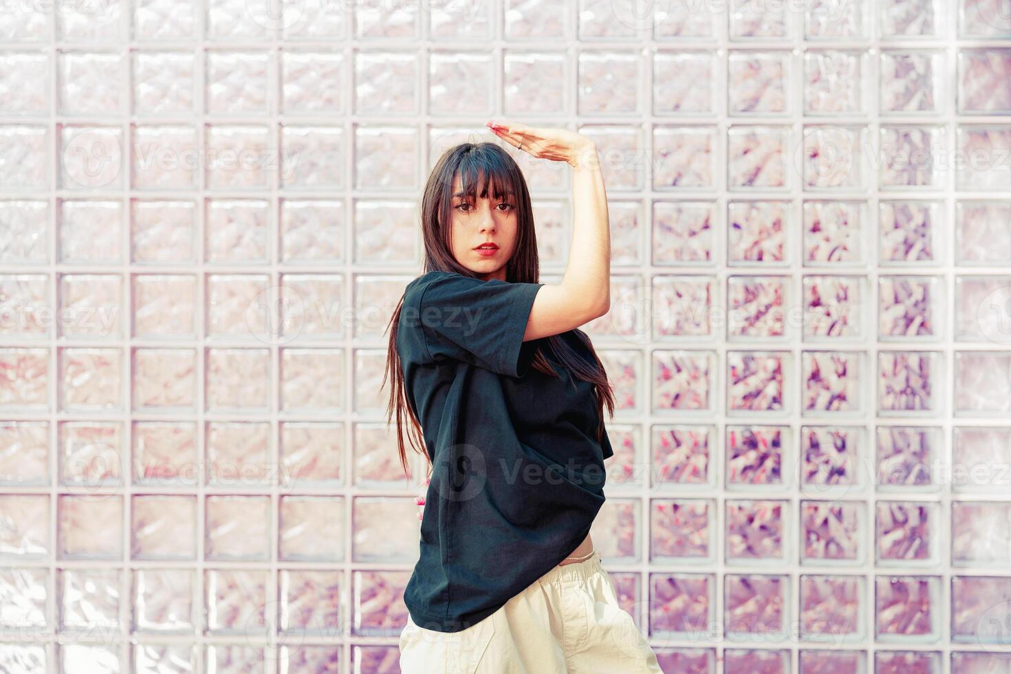 Dancer performing expressive movements against a textured glass wall in an urban setting photo