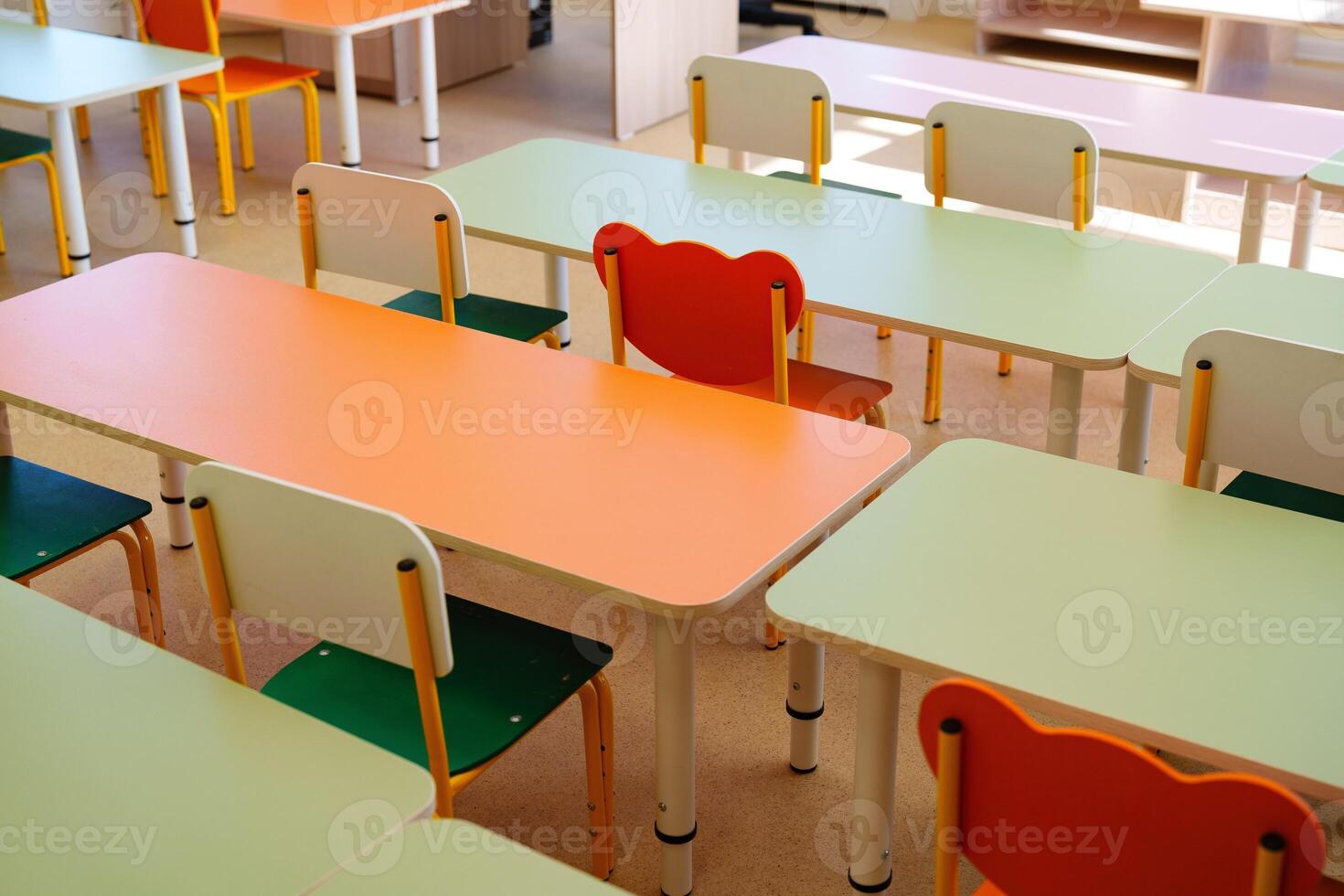 Brightly colored classroom furniture arranged in a learning space with empty desks and chairs during school hours photo