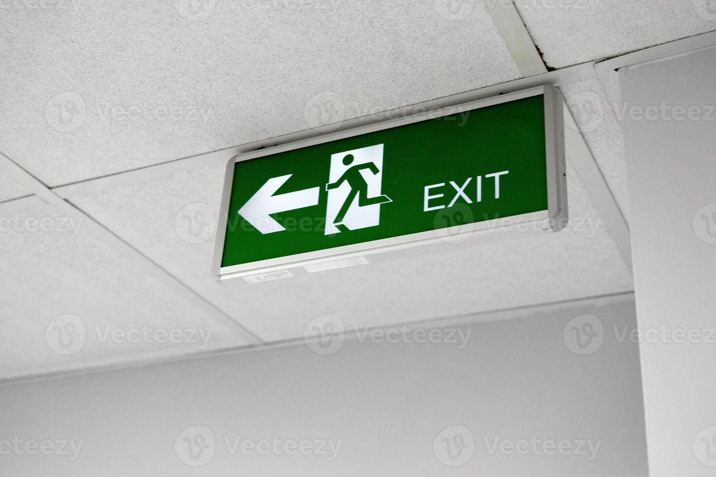 Clear exit sign directing individuals to the left in a well-lit indoor environment photo