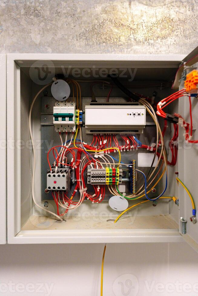 Electrical wiring inside a control box with various connected components in a modern building setting photo