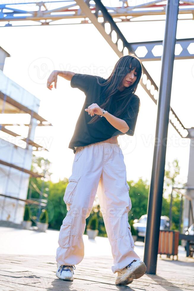 Dancer performs expressive movements in a stylish outfit during sunset at an outdoor urban location photo
