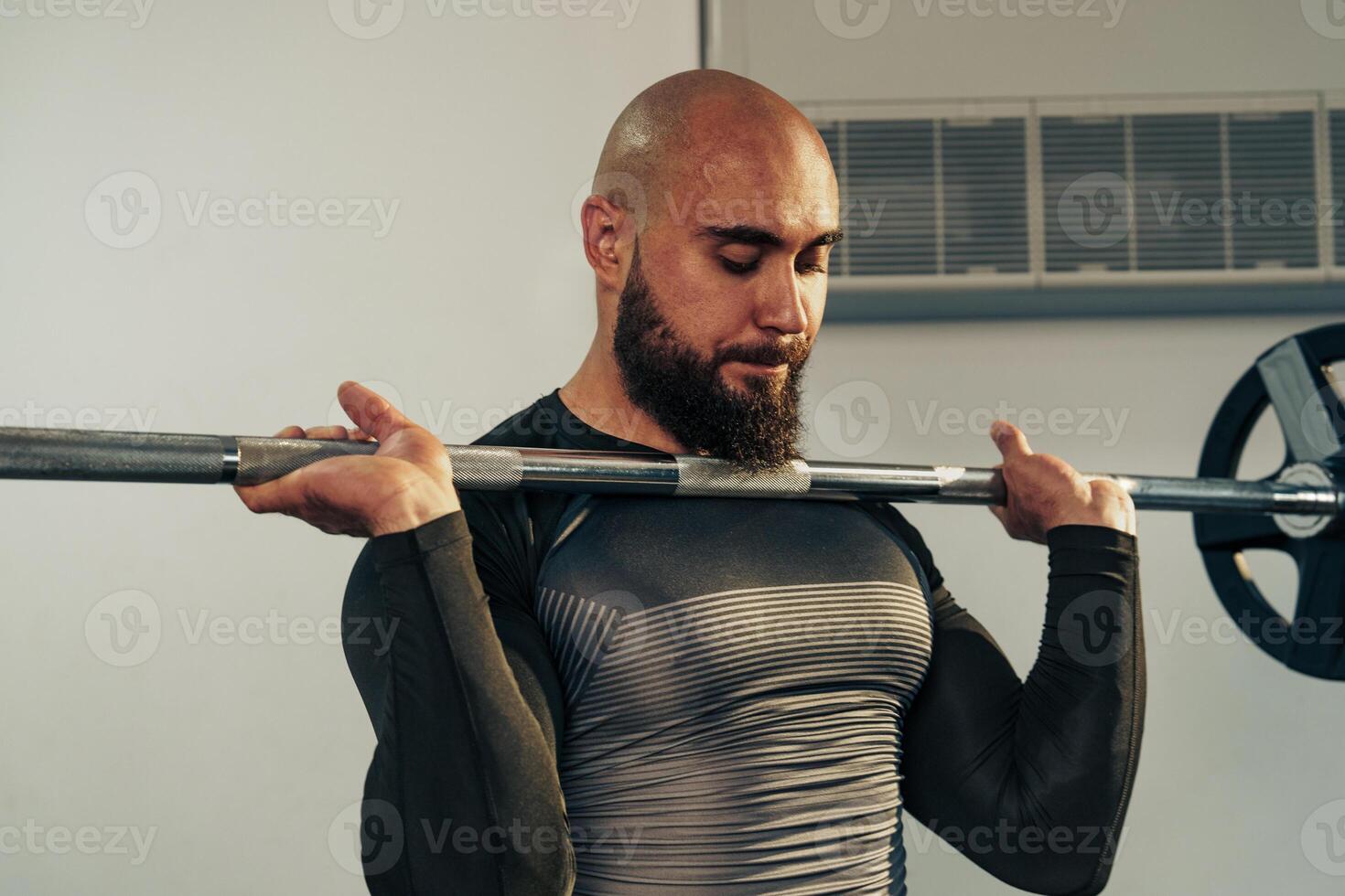 Strong man lifting barbell in a gym during strength training session to build muscle and improve fitness photo