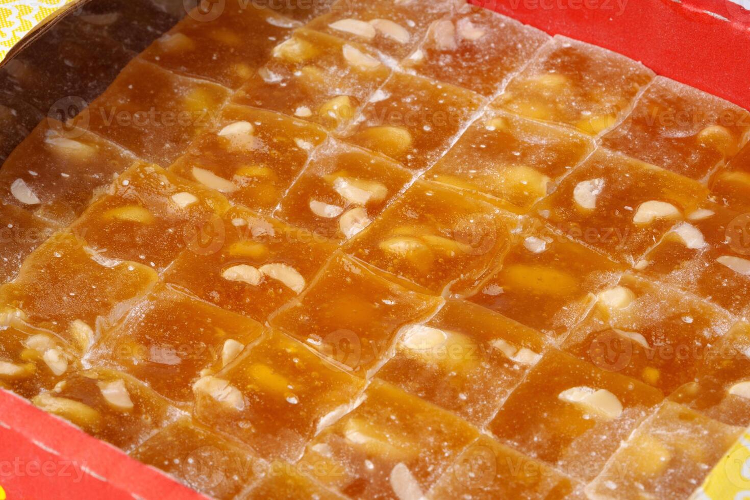 Deliciously prepared traditional Indian sweet cut into squares with cashews and served in a vibrant red box photo