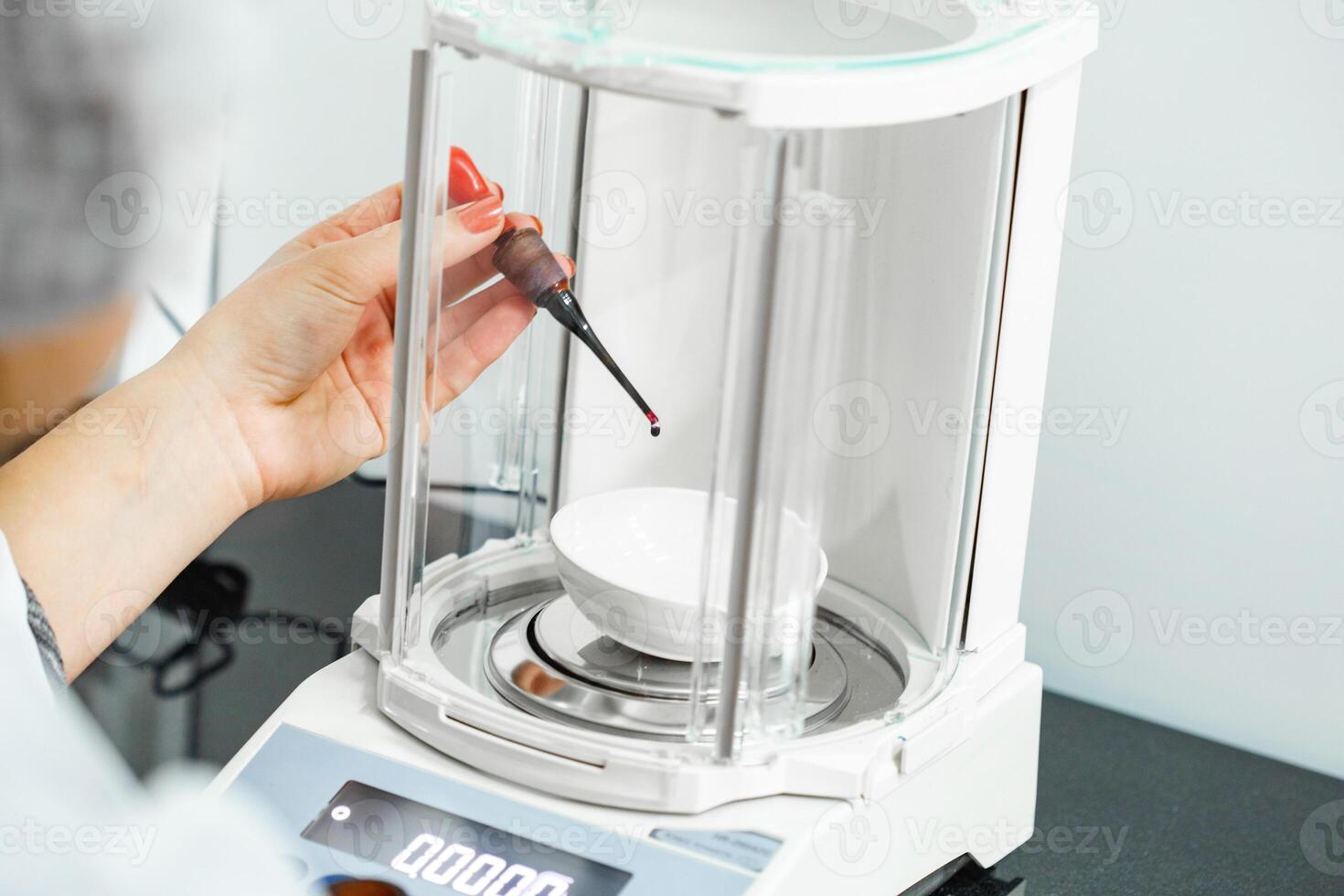 Precision weighing of liquid in a laboratory setup with an analytical balance during a research experiment photo