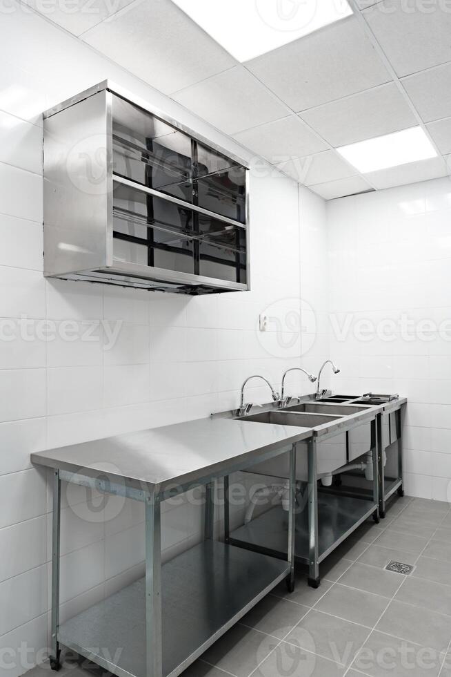 Clean stainless steel kitchen setup with washing stations and ample counter space for food preparation photo