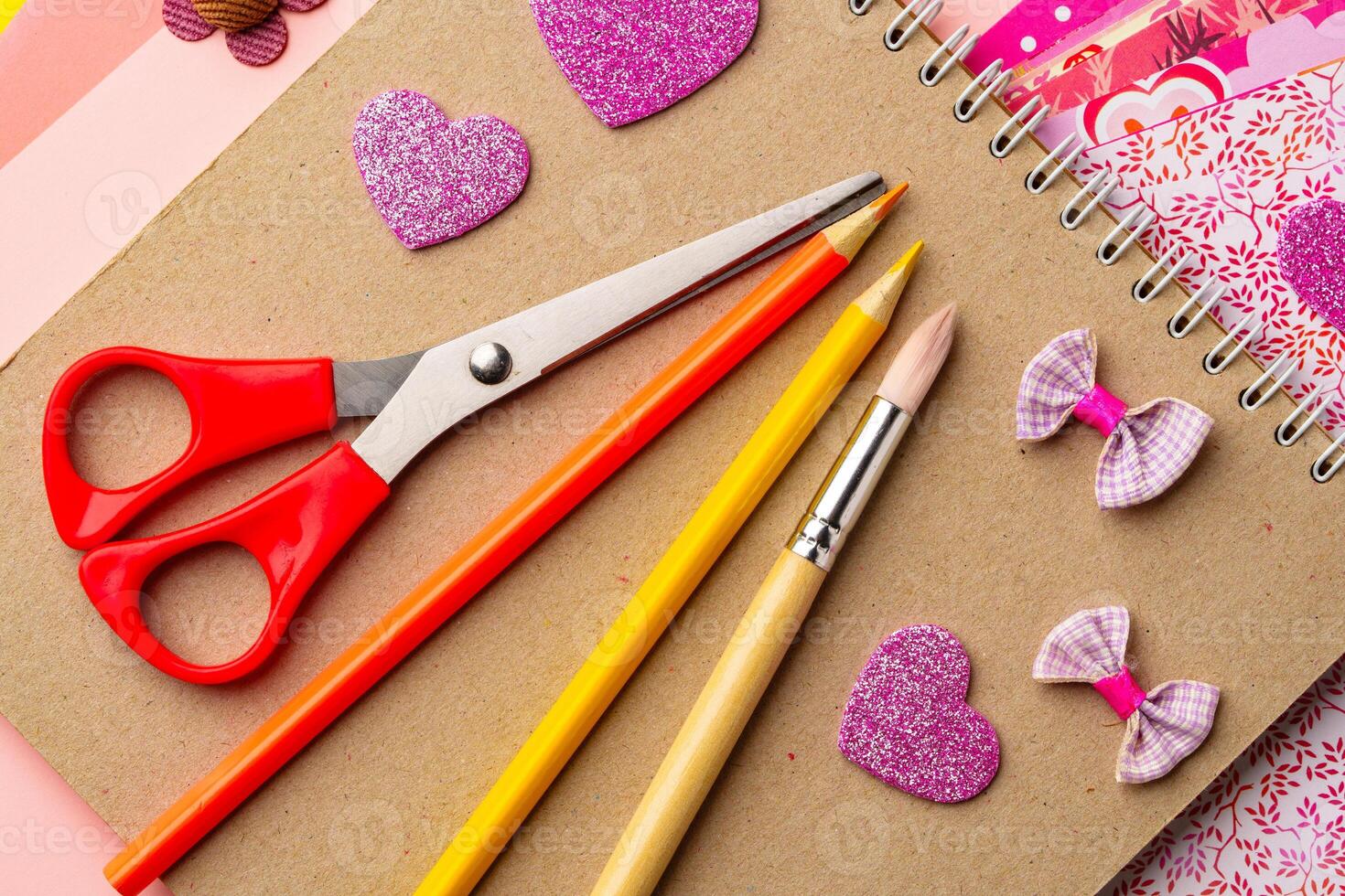 Craft supplies arranged on a tabletop featuring scissors, colored pencils, and decorative heart shapes created for a creative project photo
