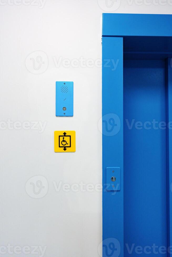 Bright blue elevator entrance features accessibility sign and intercom in a modern building photo
