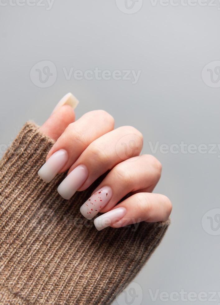 Woman showing stylish manicure with brown sleeve on grey background photo