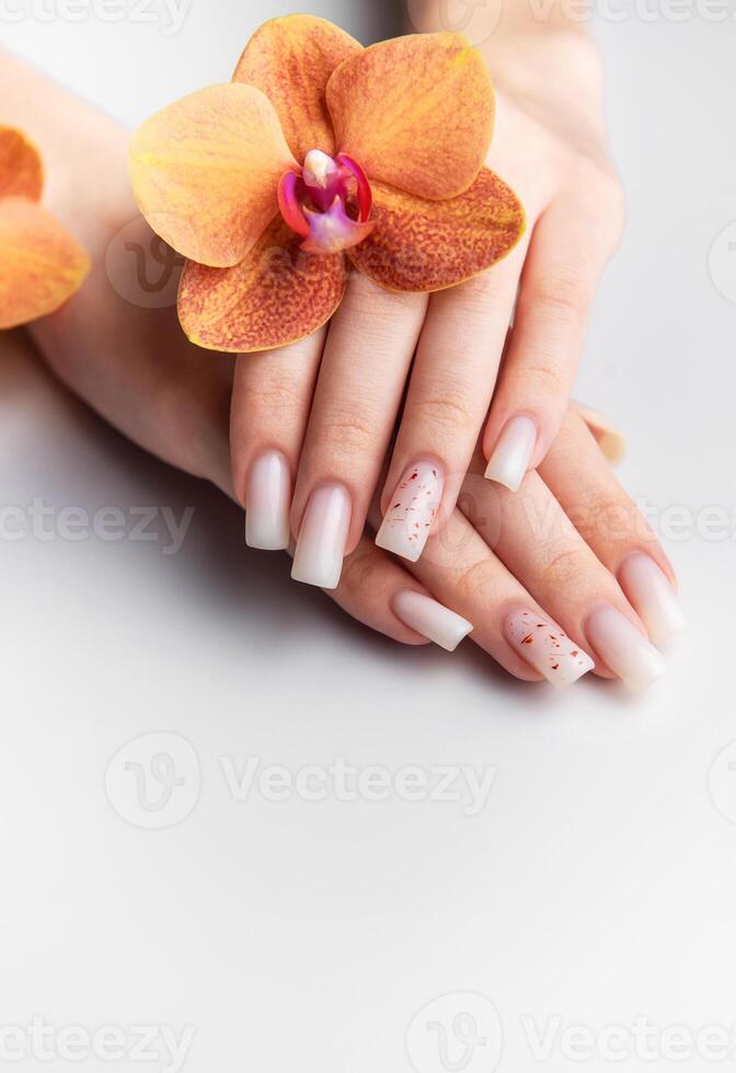 Woman showing white nails with orchid decoration photo