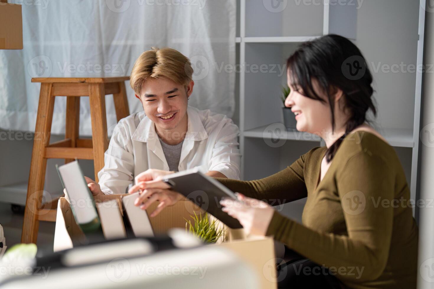 Couple happily unpacking books and decor items in their new home, sharing ideas and smiles photo