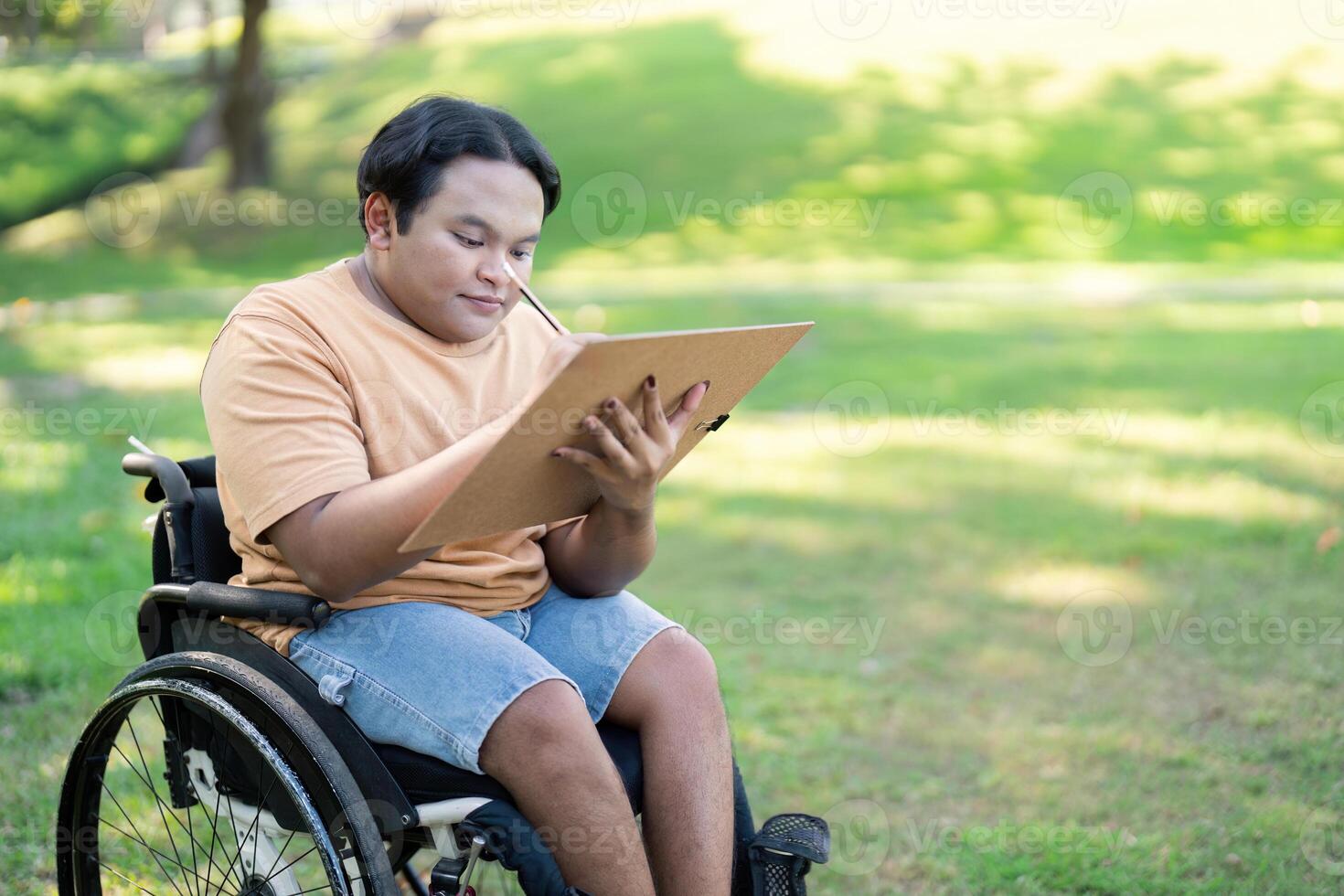 Disabled artist in wheelchair concentrating on sketching nature in a tranquil park photo