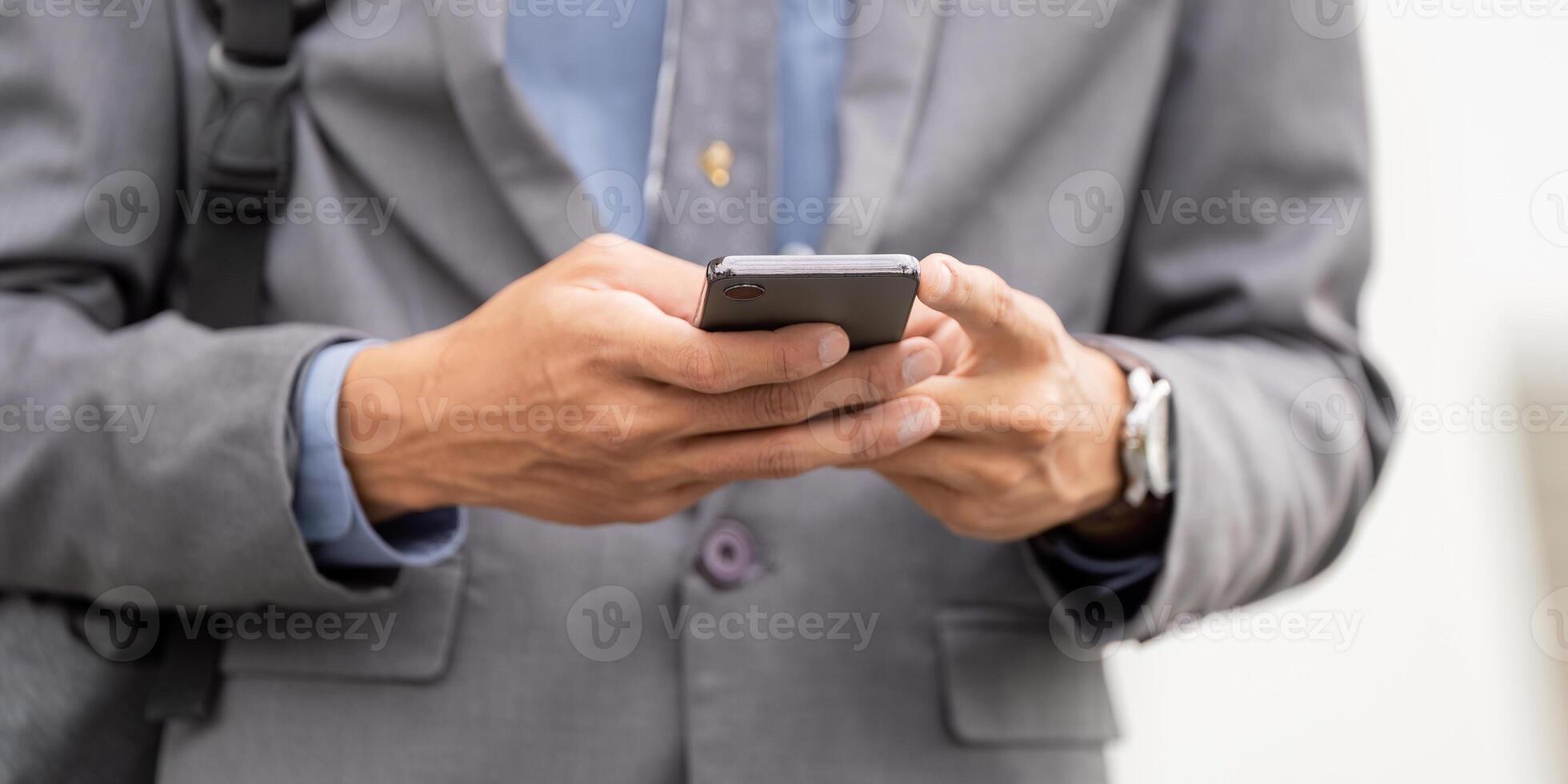 Close up of young Asian businessman using smartphone to send messages, dressed smartly in a suit photo