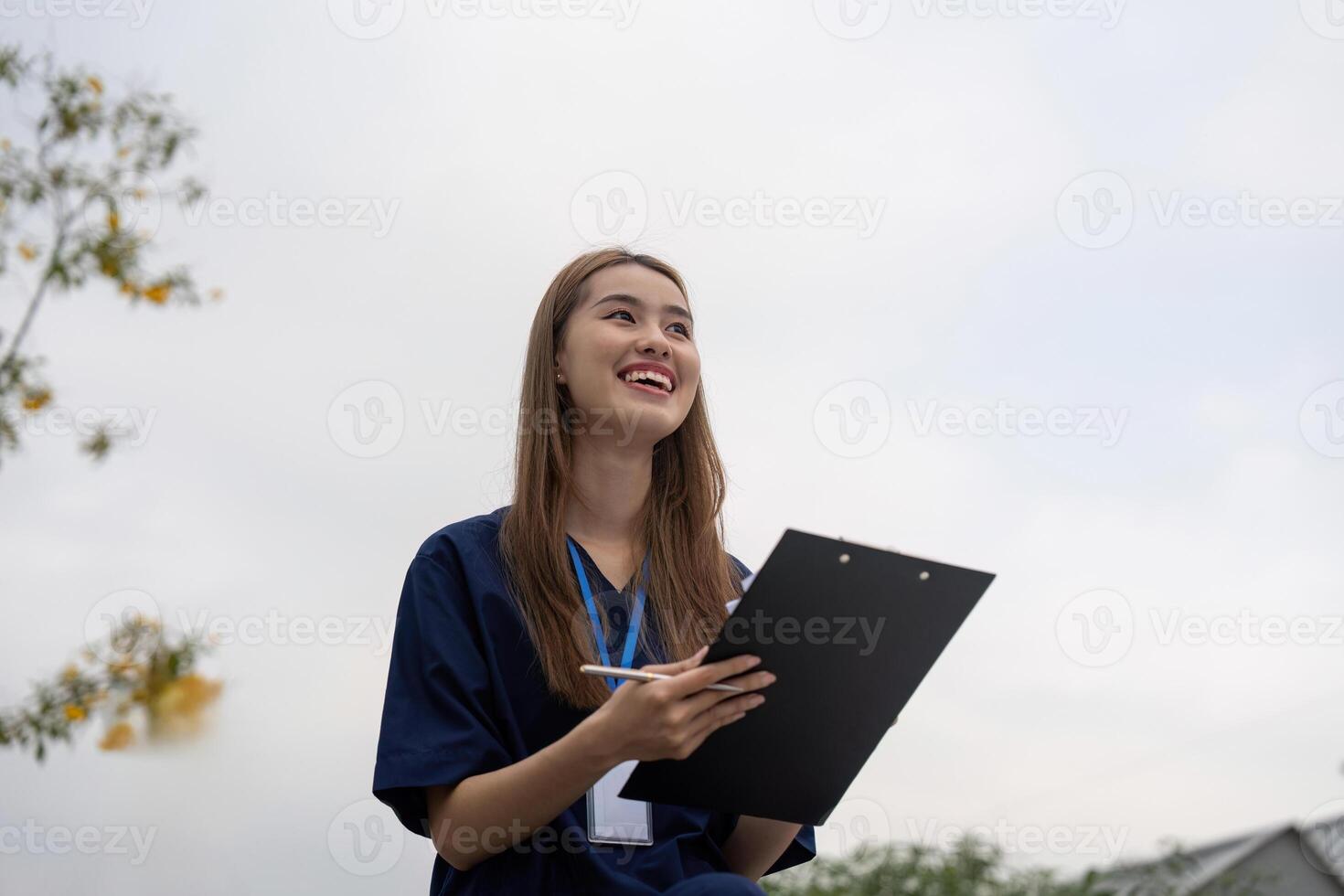 Nurse smiling while reviewing patient notes on a clipboard during a break photo