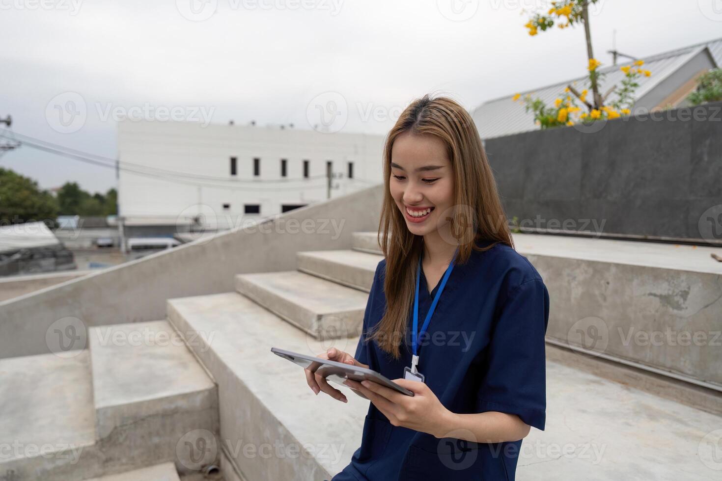 Nurse smiling while using a tablet for patient care during a break photo