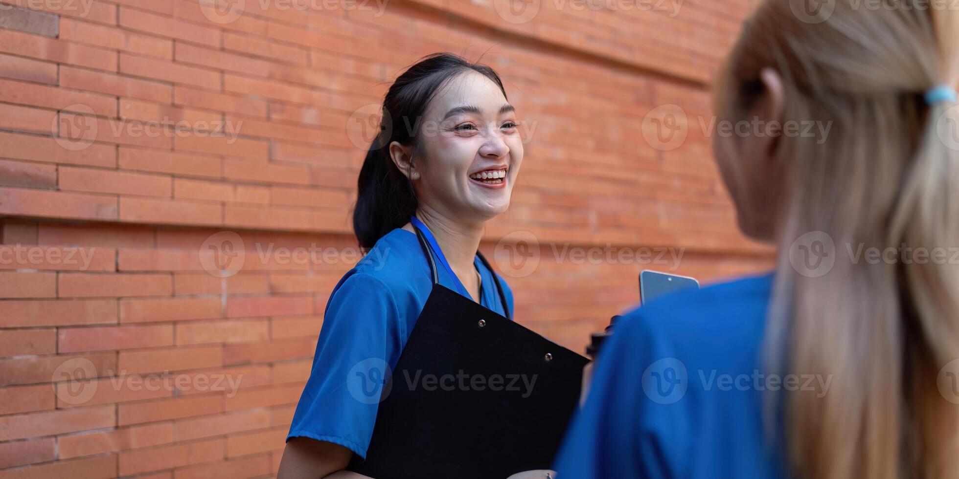 Doctors smiling and conversing during a break with a clipboard. photo