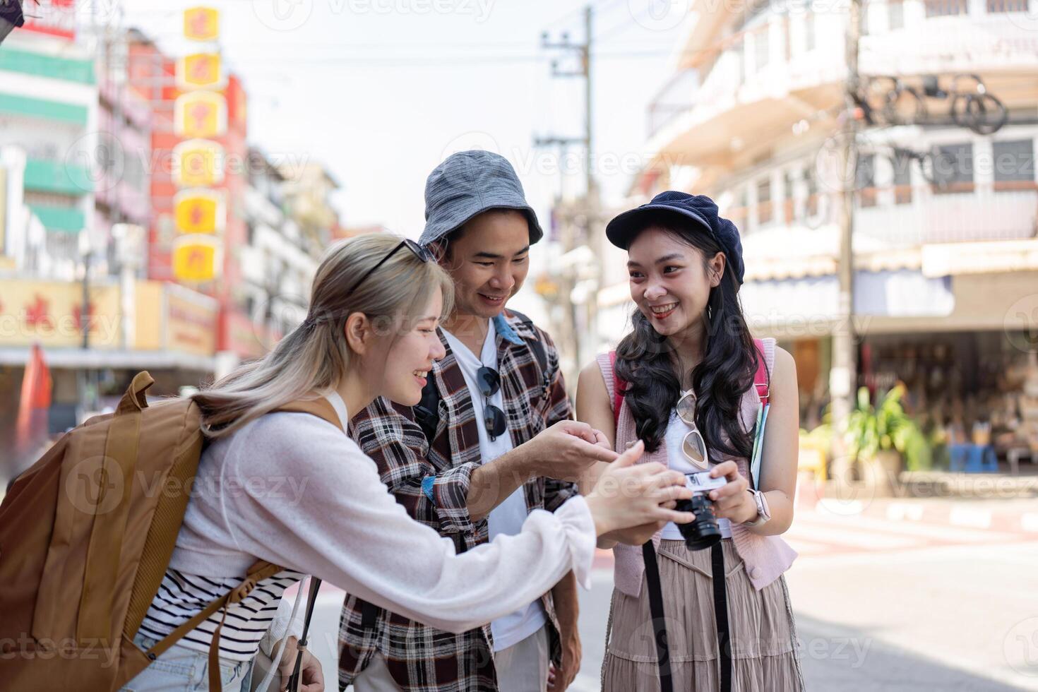 Diverse group of friends reviewing photos together on a bustling street, capturing travel memories and enjoying their time in the city.